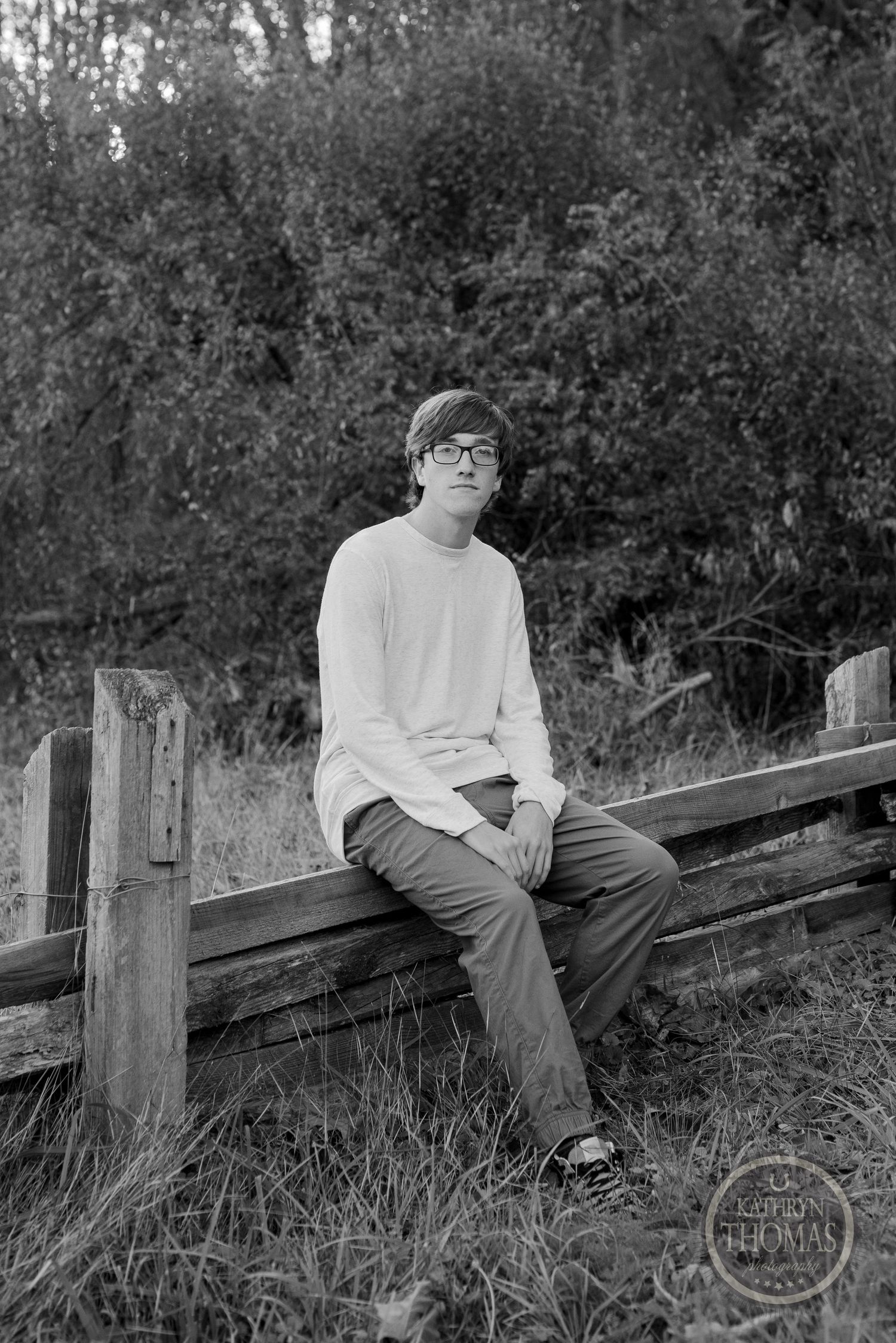 Black and white portrait on wooden fence in natural setting.