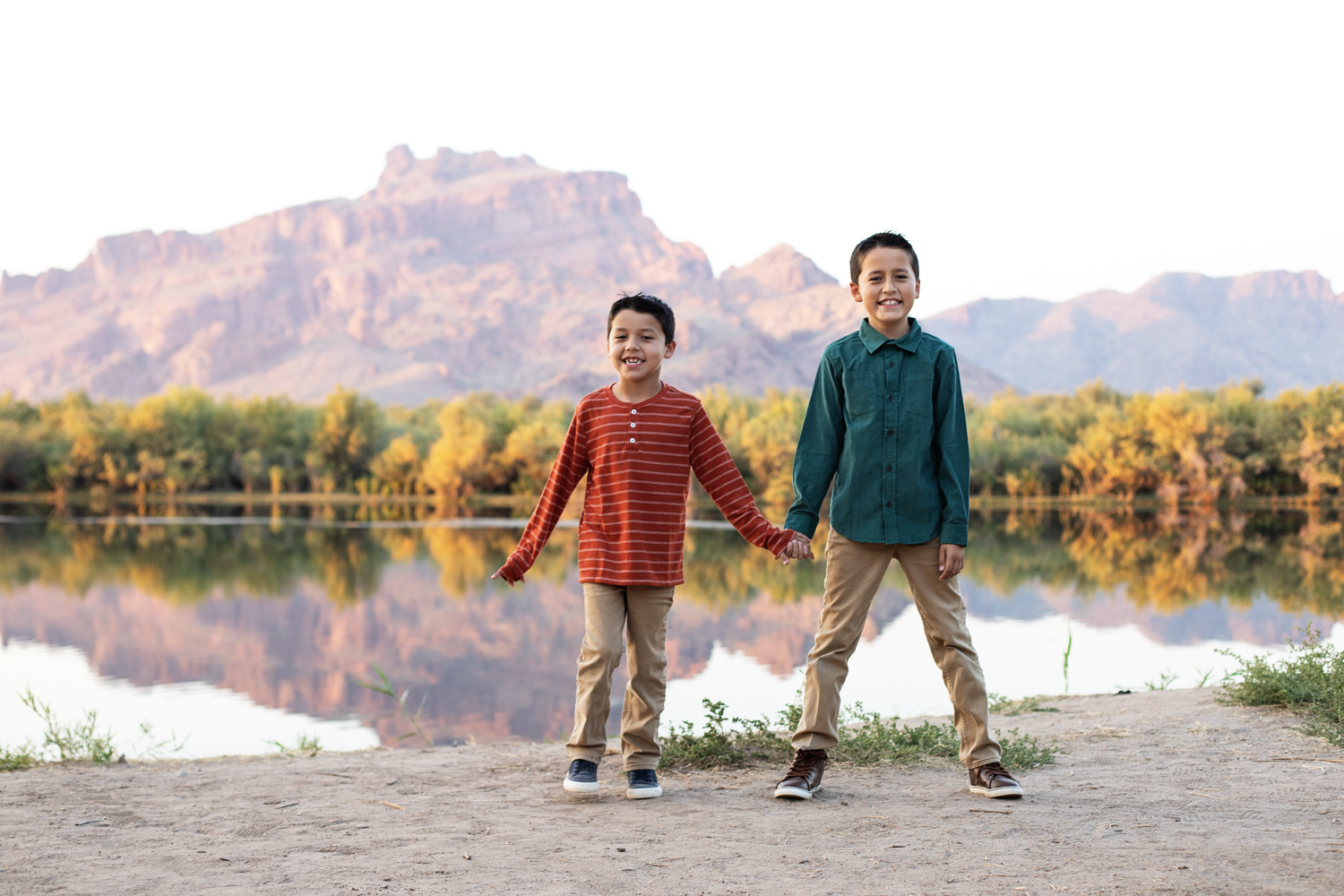 Family posing together outdoors with mountain and lake landscape in background.