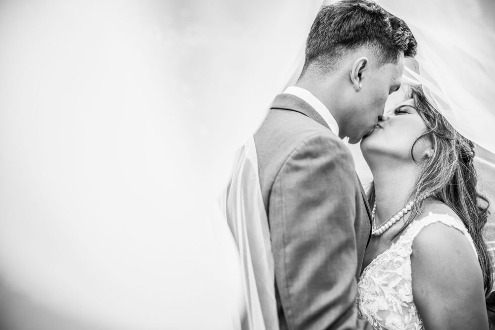 Black and white romantic wedding photograph capturing a tender kiss between the bride and groom.