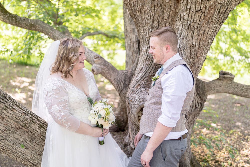 A romantic outdoor wedding moment captured under a large tree with natural lighting and a rustic theme.