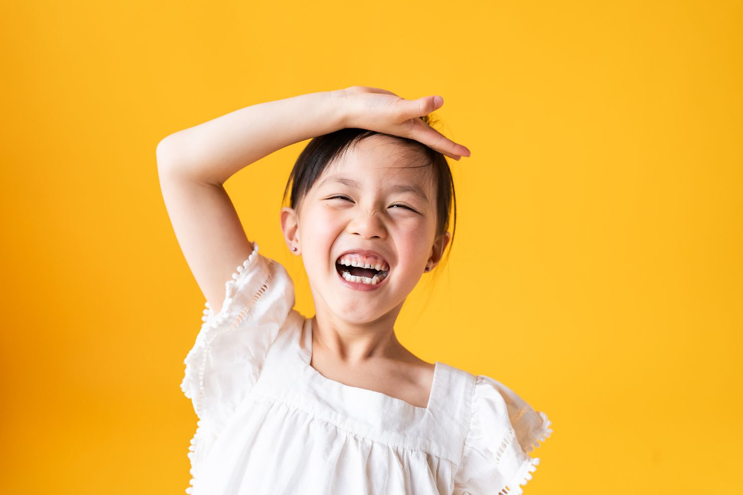 Girl making a silly pose in front of a yellow backdrop at North City Studio