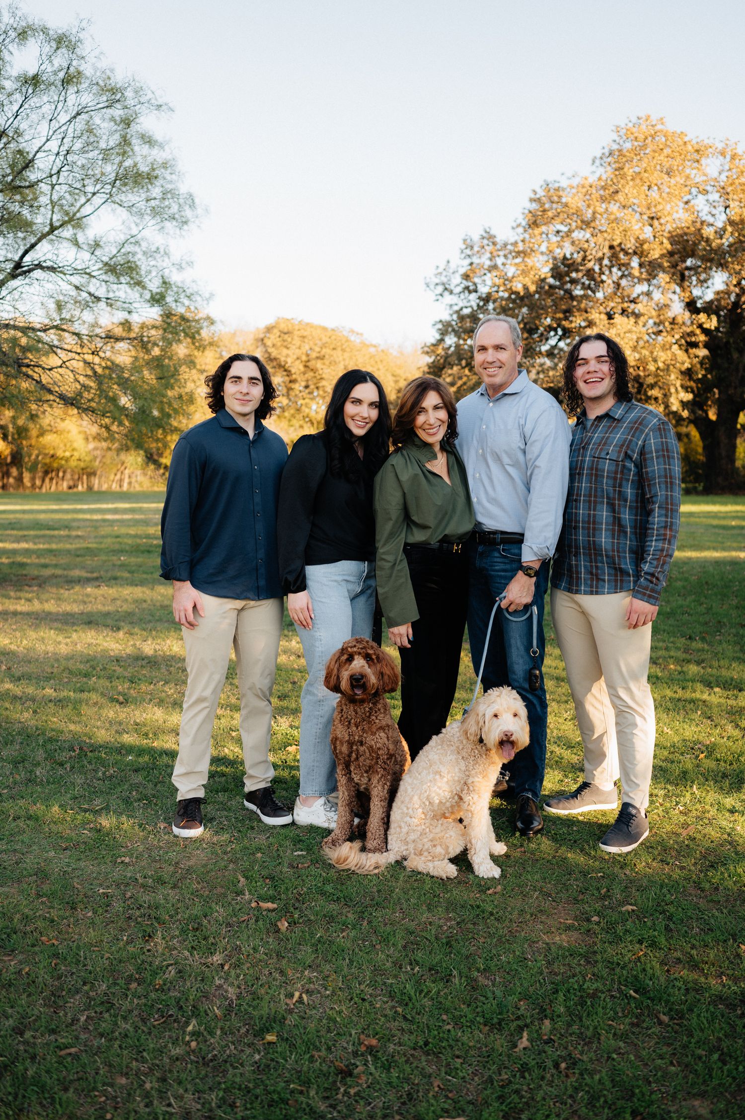 Family portrait outdoors with their two dogs on a sunny autumn day.