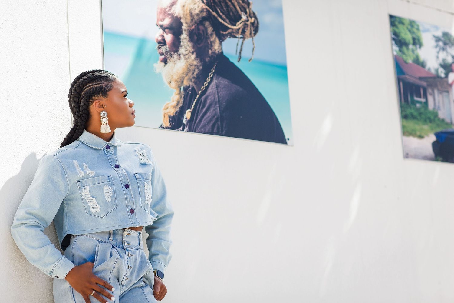 Woman in denim outfit views photography exhibition displayed on white wall indoors.