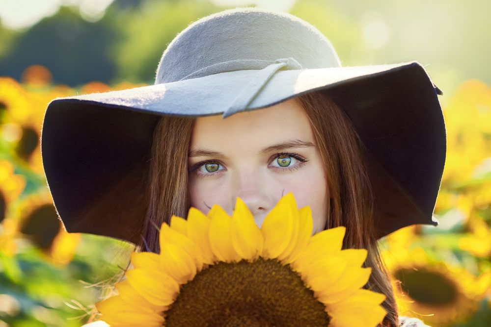 young lady peaking over sunflower
