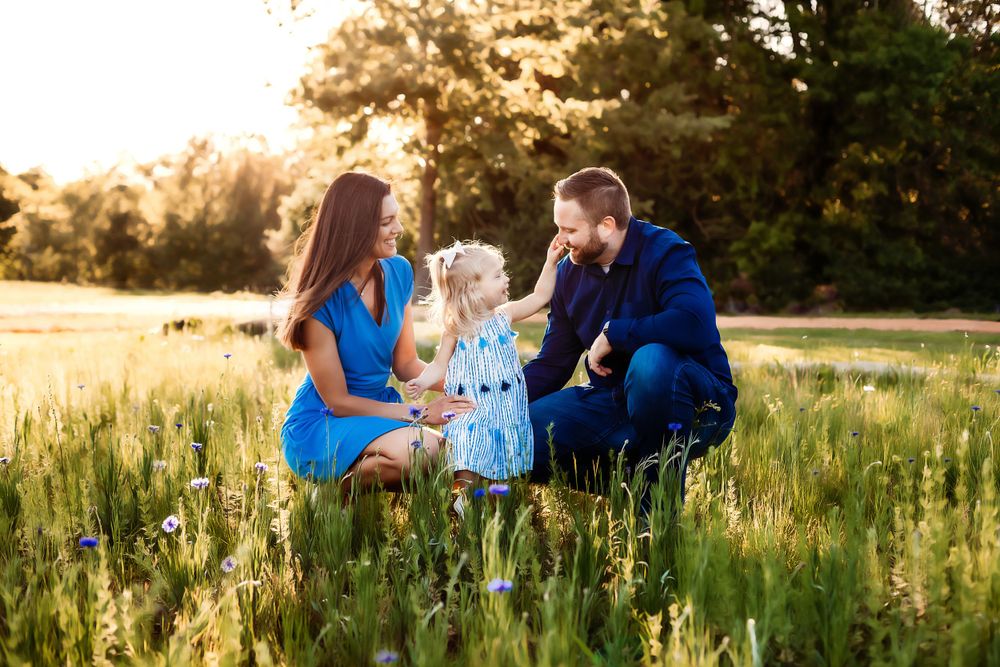 Family portrait session in a golden sunlit meadow during sunset.