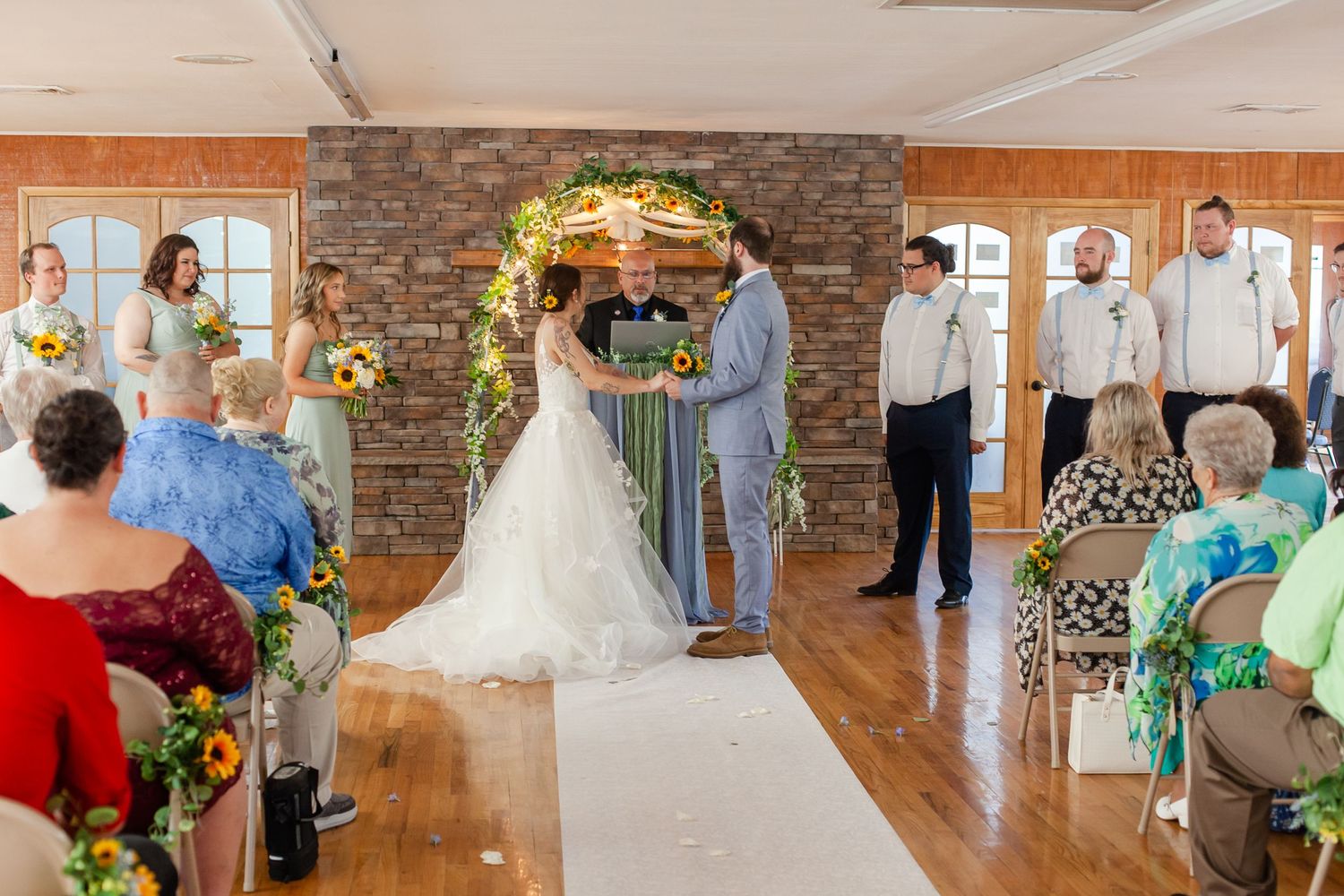 Wedding celebration candid moments captured in a rustic venue with stone accent wall.