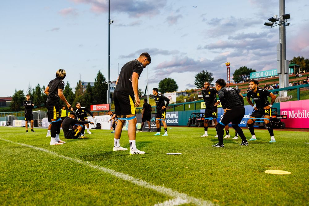 Soccer team practices on training field during golden hour.