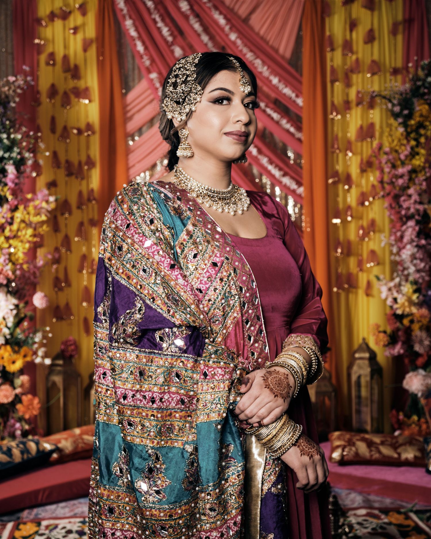 Ornate South Asian bridal fashion featuring intricate embroidery and traditional jewelry against a colorful backdrop.
