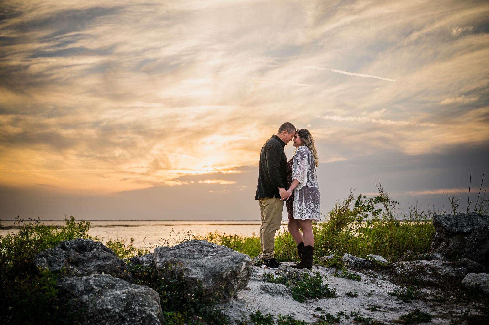 man and woman engagement photo posing with their foreheads together on Okeechobee lake at sunset