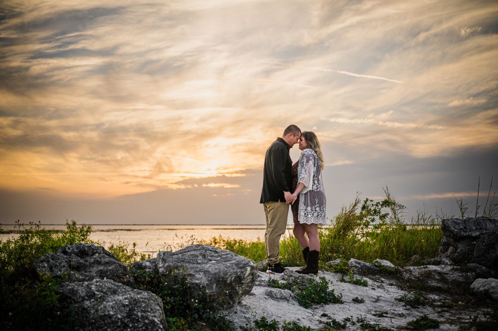 man and woman engagement photo posing with their foreheads together on Okeechobee lake at sunset