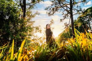 pregnant woman looking over her shoulder surrounded by trees and blue sky