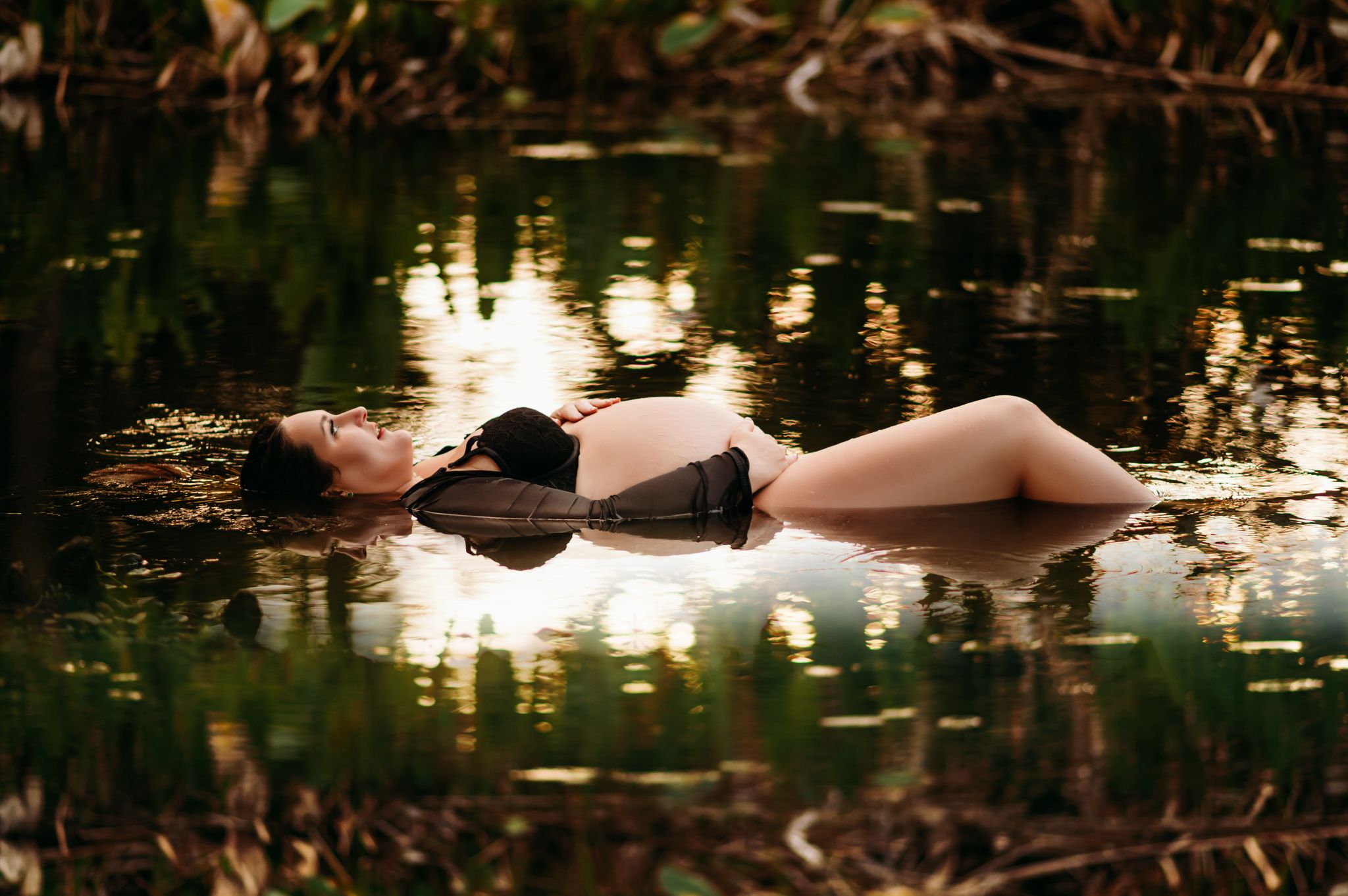 pregnant plus size woman posing on her back in florida fresh water