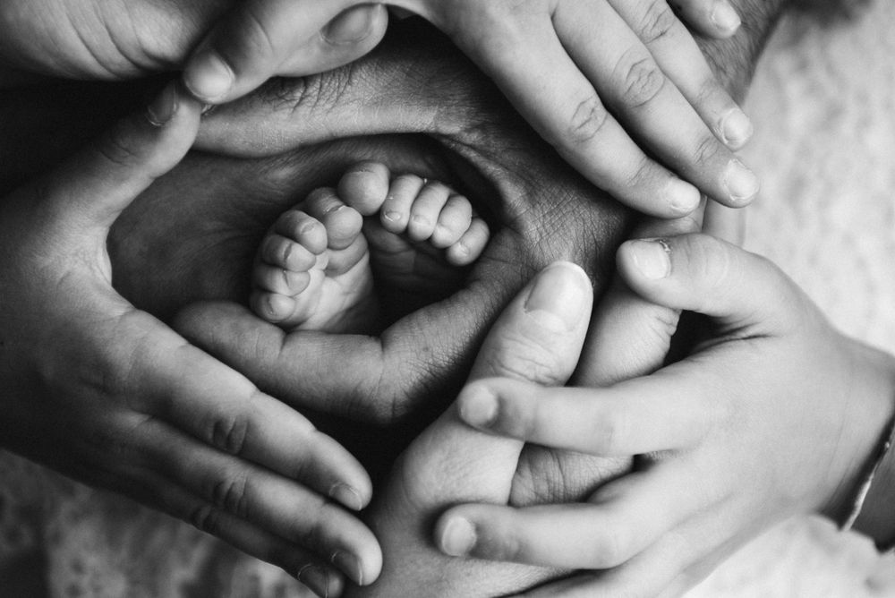 Black and white artistic photo of tiny baby feet cradled in hands.