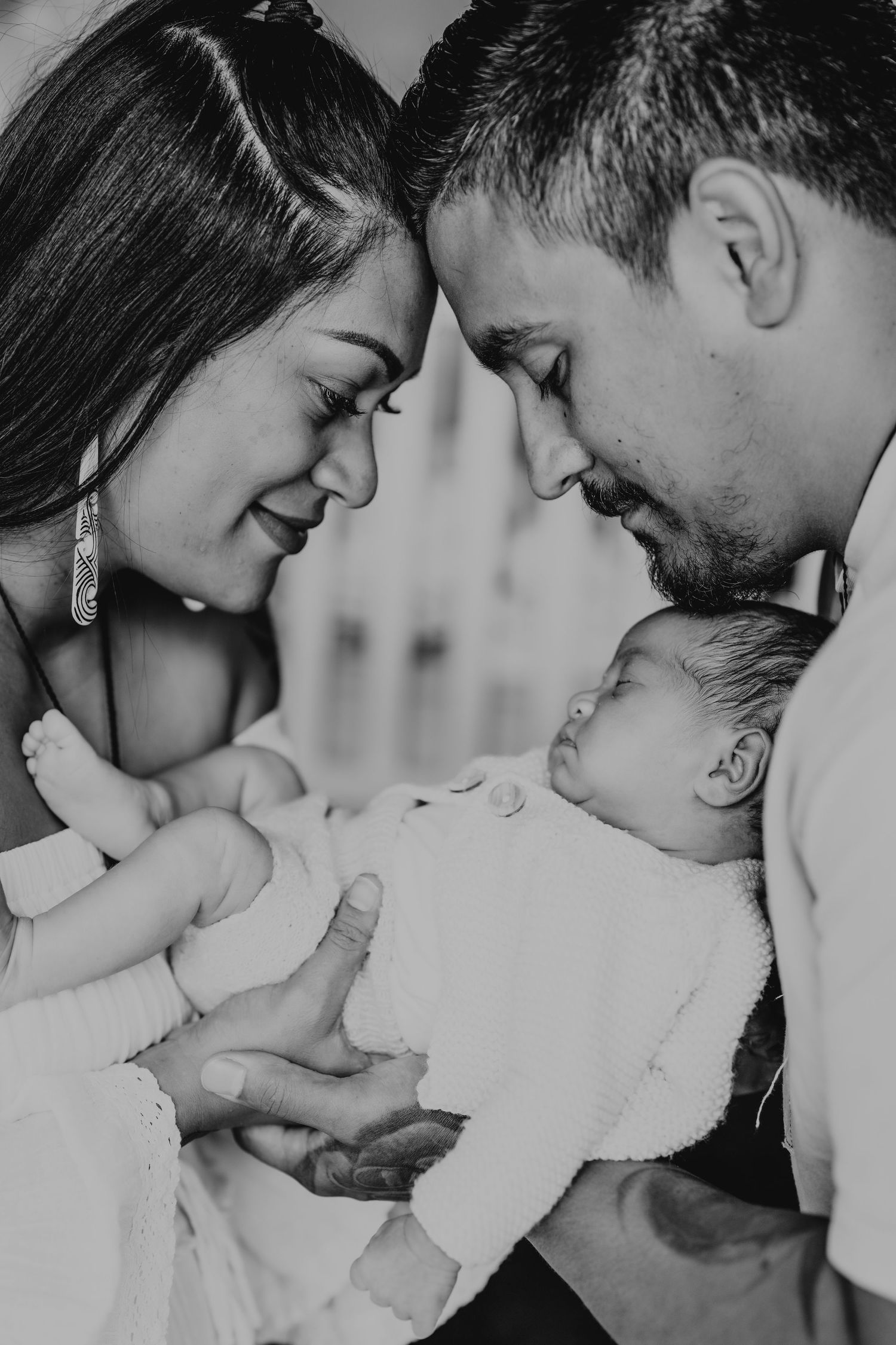 An intimate black and white portrait of a tender family moment with a newborn baby.