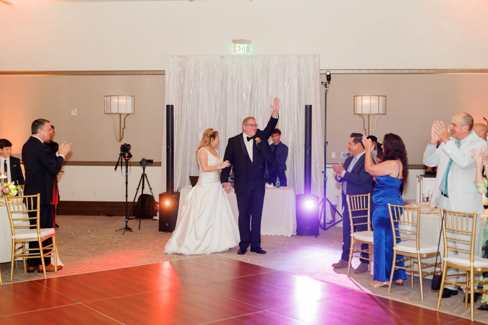 Wedding reception venue with white draping and guests seated at decorated tables.