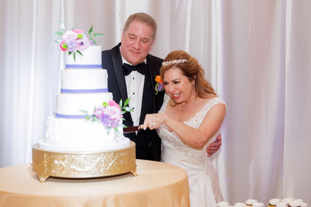 A traditional wedding cake cutting moment at an elegant reception with a white and gold tiered cake.