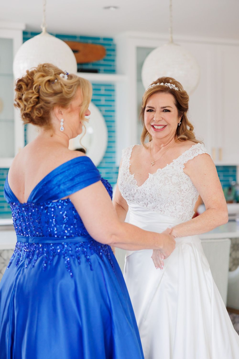 A wedding moment captured with royal blue and white gowns in a bright modern setting with pendant lighting.