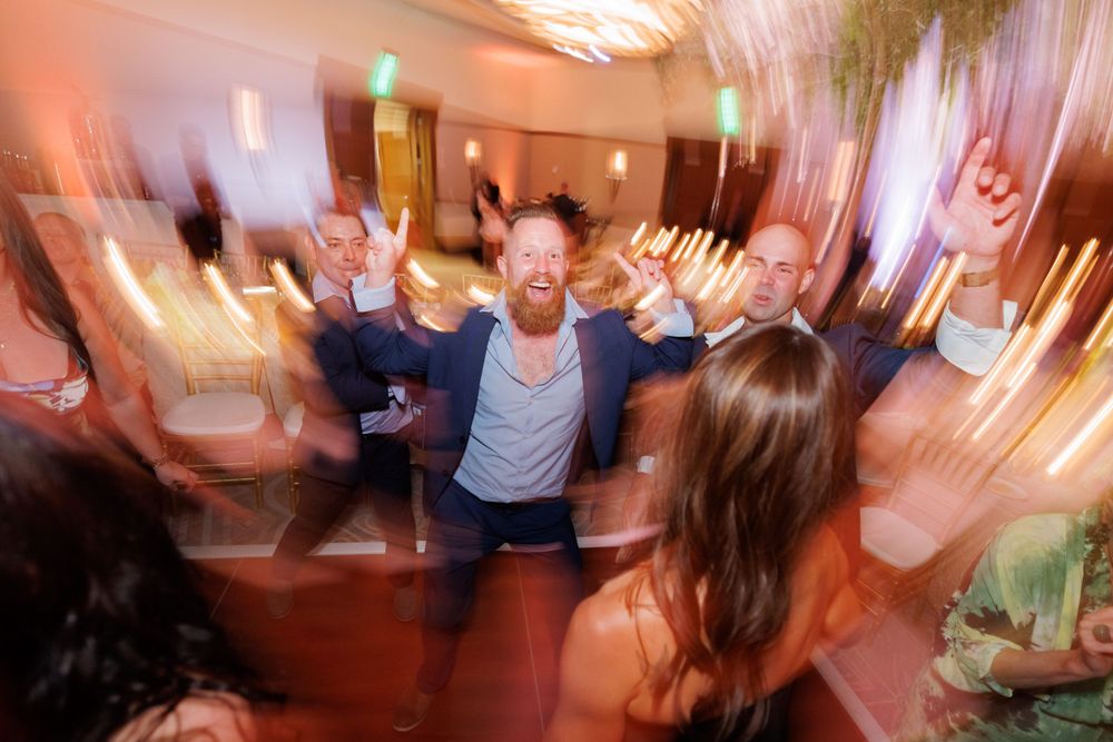 Dynamic motion-blur photograph of guests dancing and celebrating at a wedding reception.