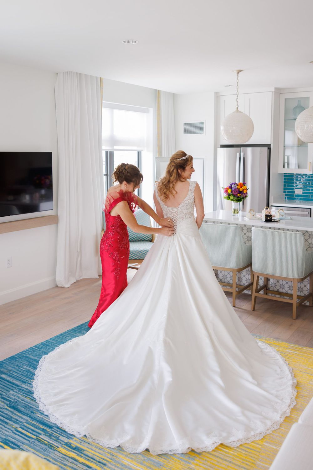 A wedding dress with a long train being adjusted in a modern, bright interior setting.