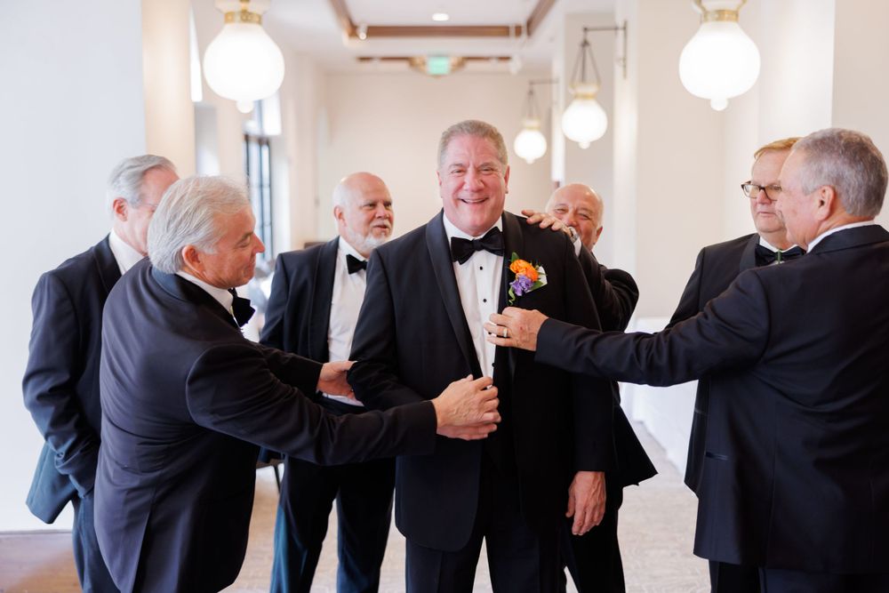 A lively group of groomsmen in black tuxedos enjoying a celebratory moment.