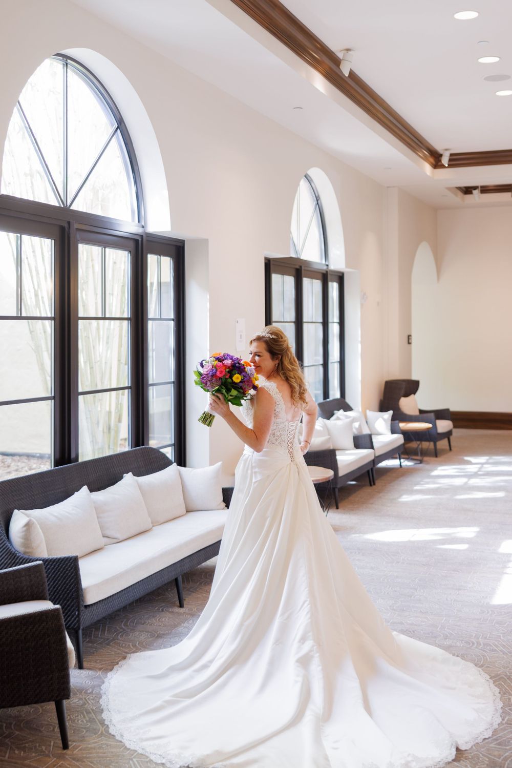 A stunning bridal portrait in a sun-lit venue featuring arched windows and modern furniture.