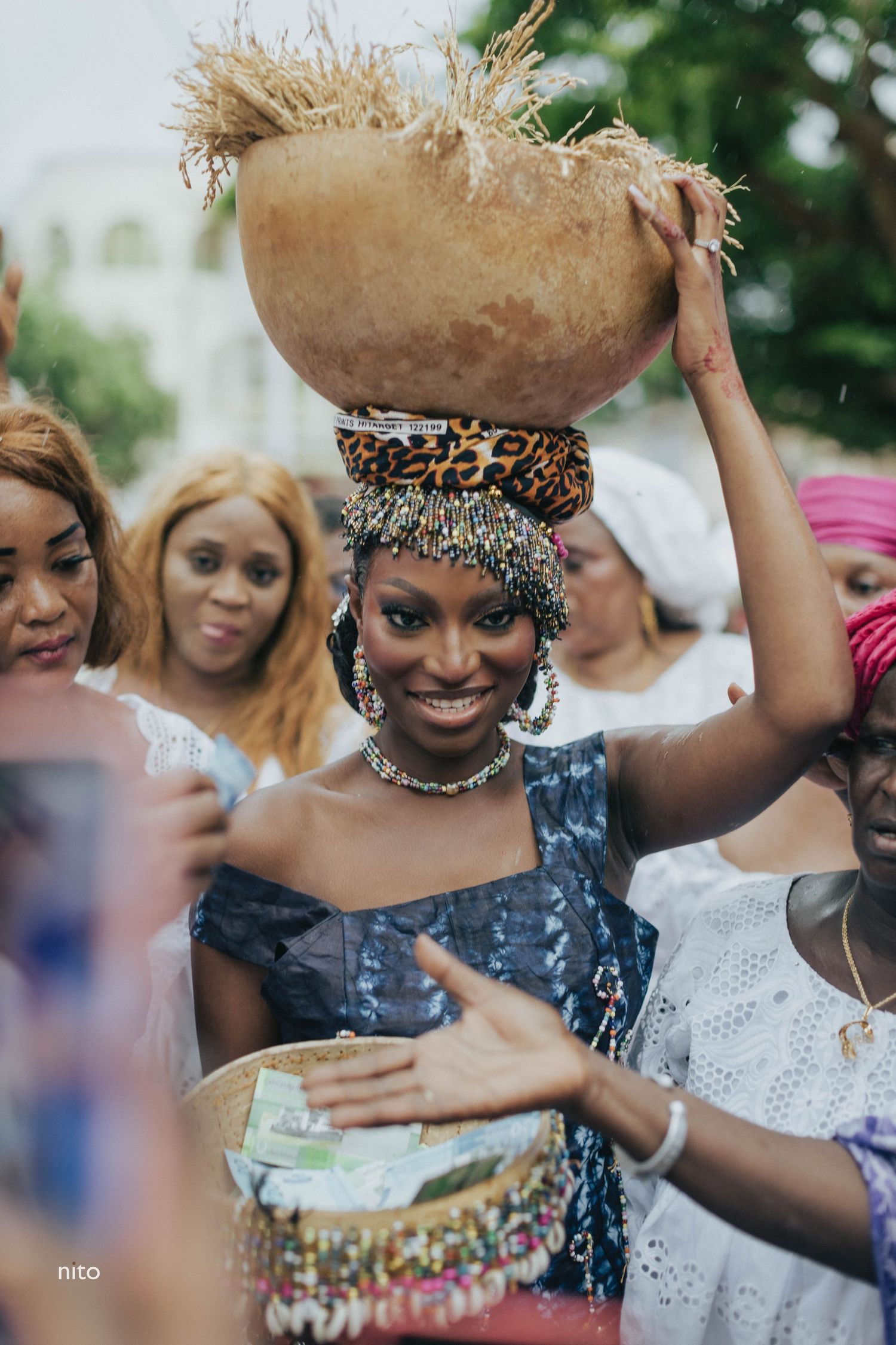 A traditional cultural ceremony with a woven basket balanced on head amid festive celebrations.