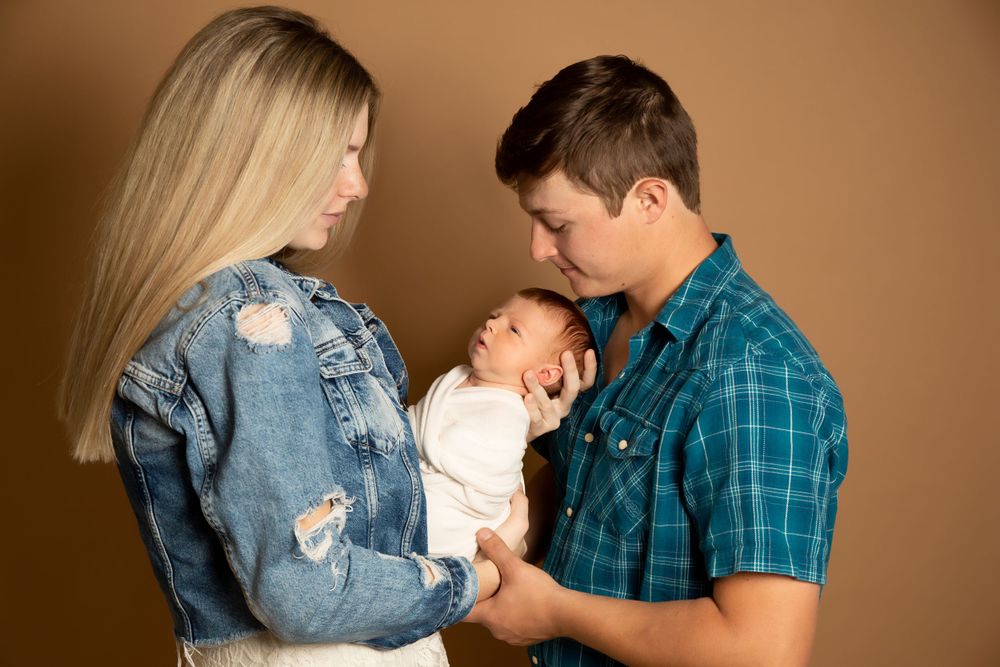Intimate family moment with newborn baby against neutral studio background.