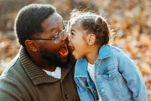 Father and young daughter making funny faces at each other.