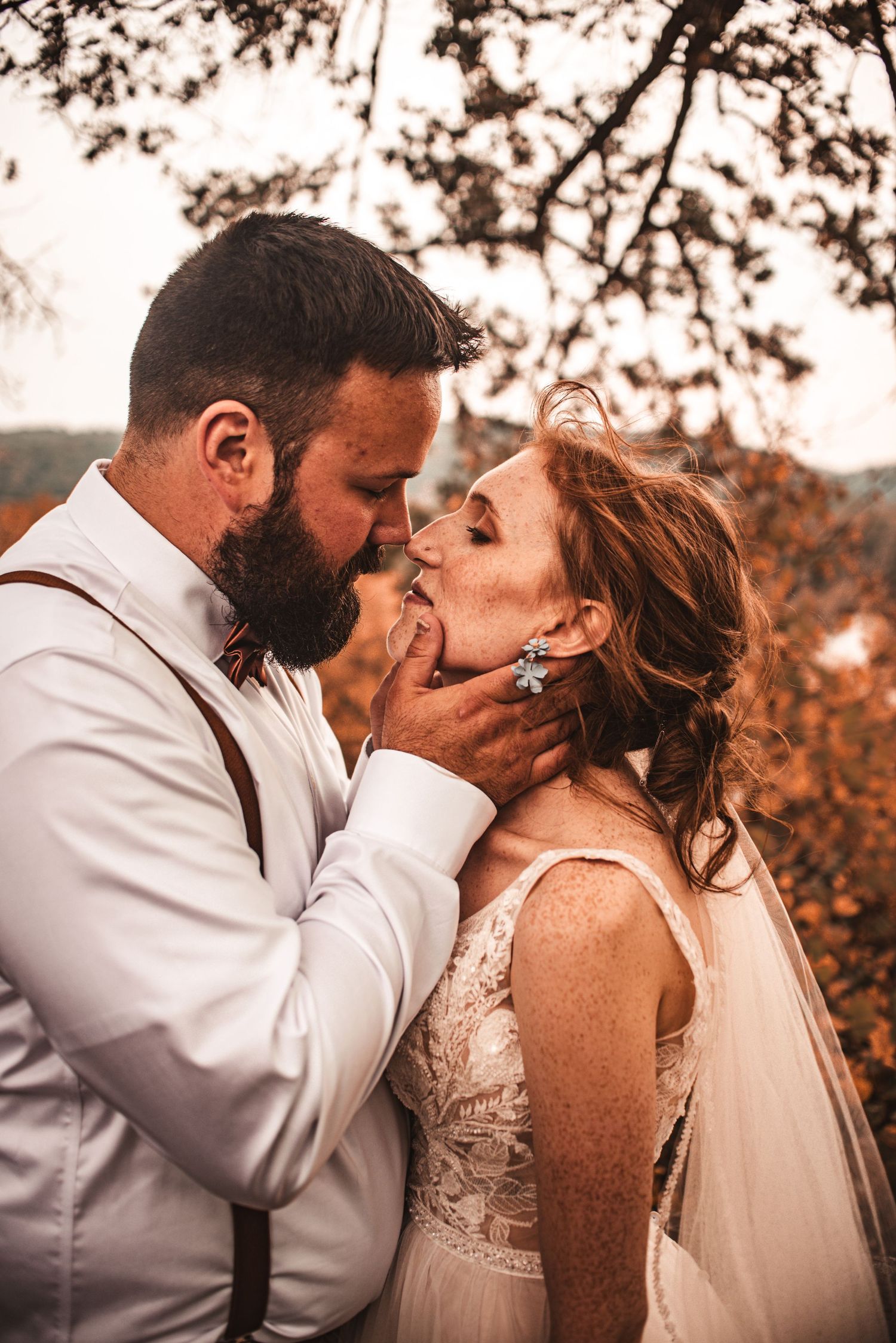 A romantic wedding portrait capturing an intimate moment in warm autumn lighting.