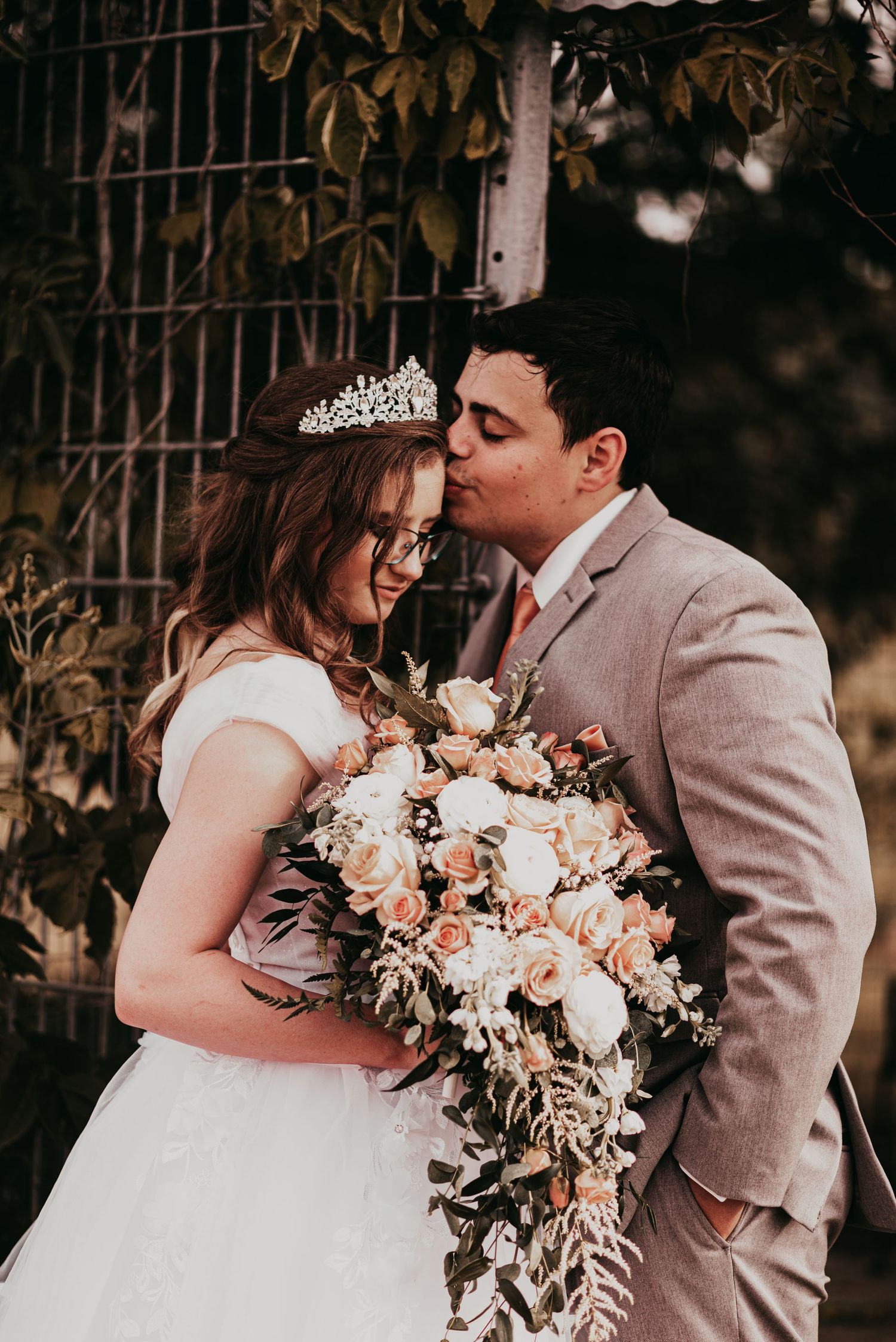 Romantic wedding moment with floral bouquet and delicate tiara in garden setting.