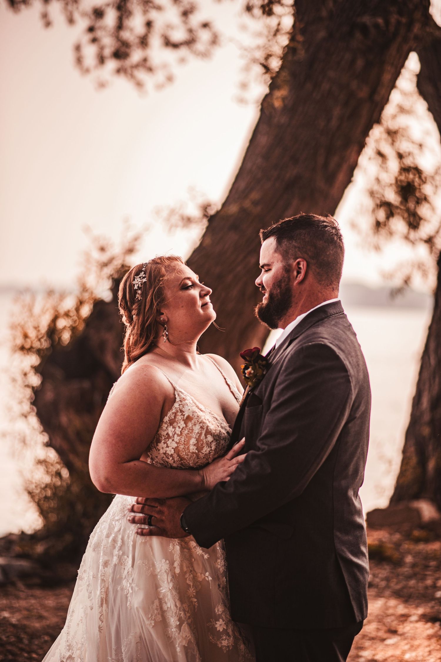 Romantic sunset wedding portrait under a large tree.