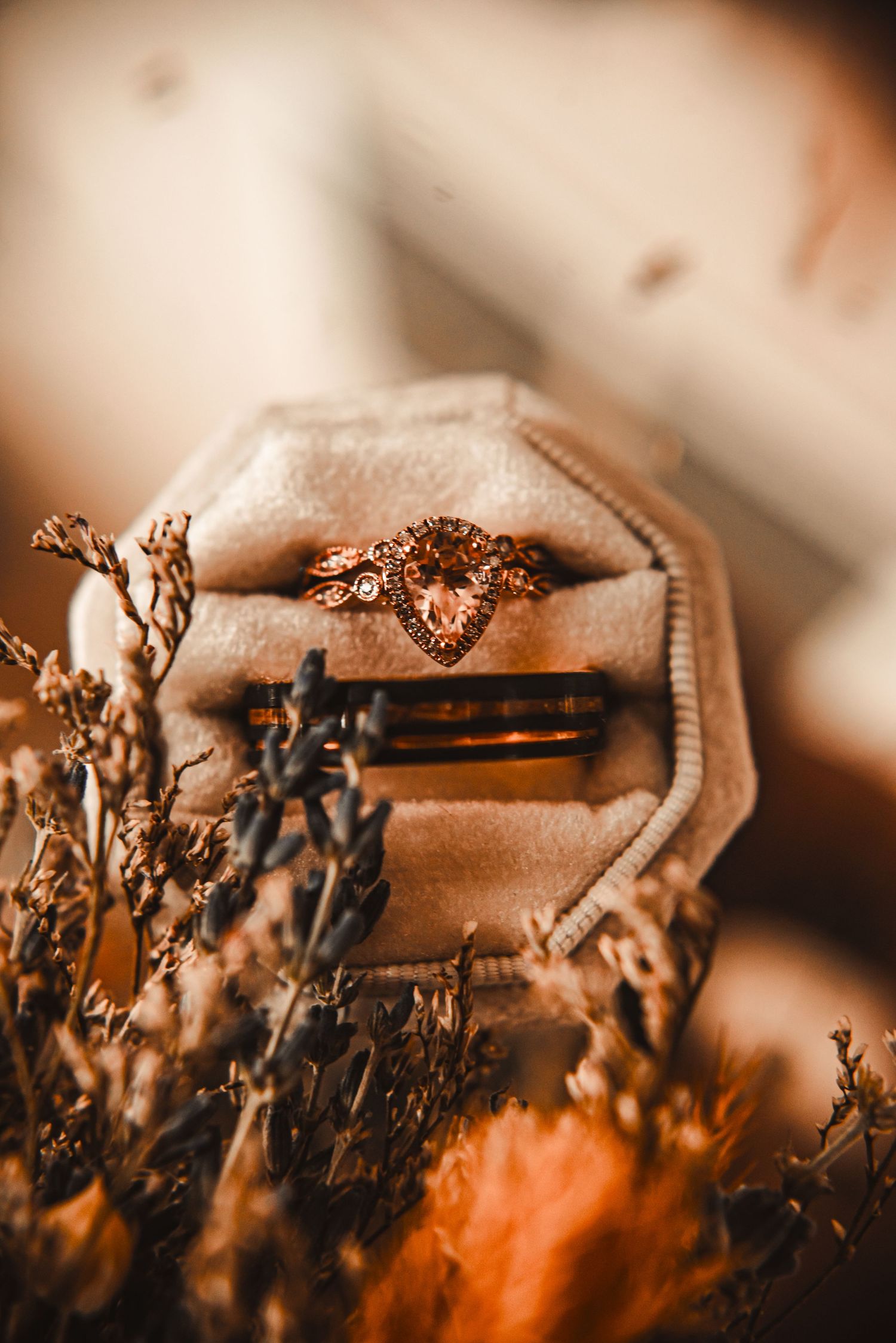 Wedding ring detail shot in vintage ring box with dried flowers and warm lighting.