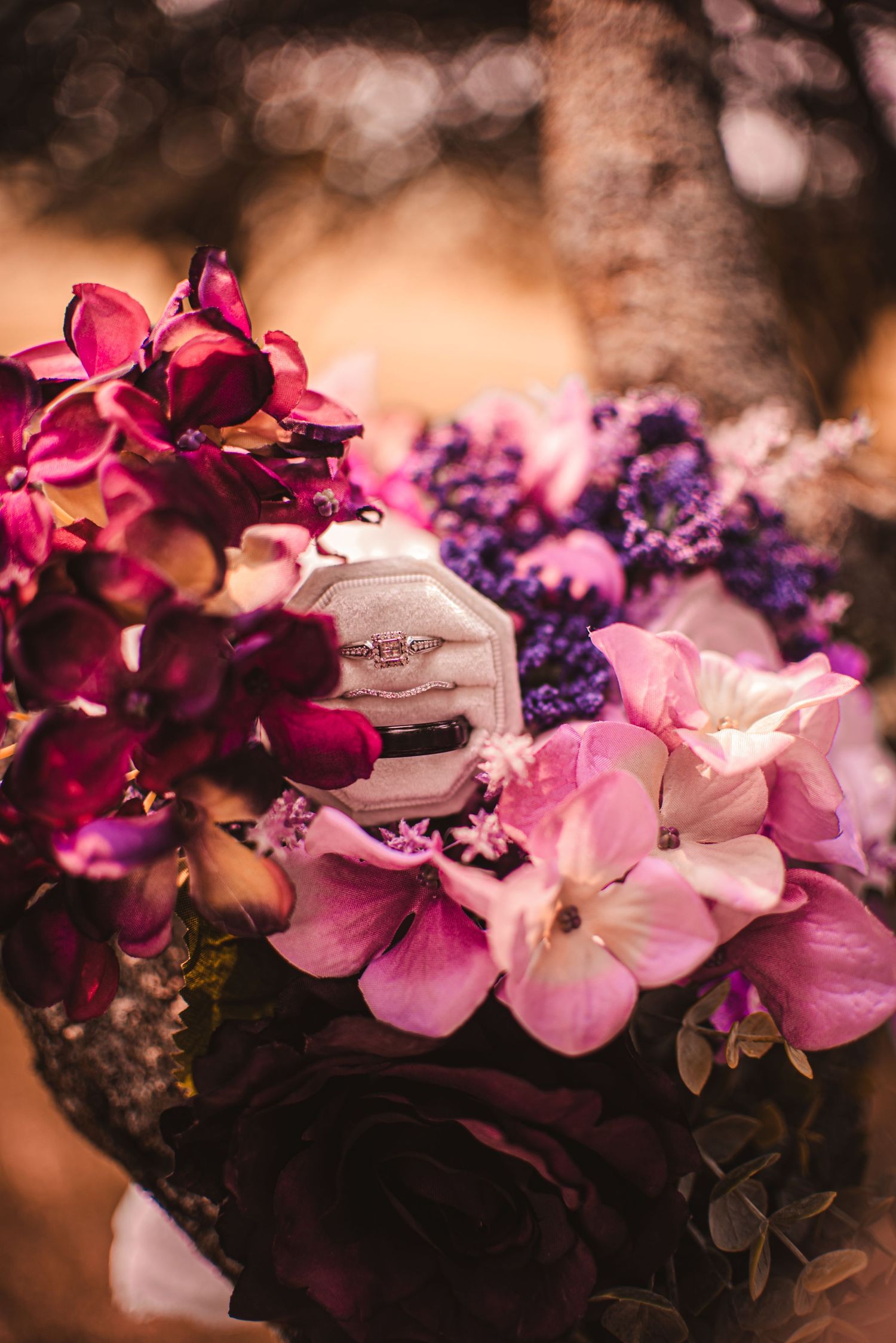 Close up of vibrant pink and purple wedding flowers with wedding rings nestled among the petals.