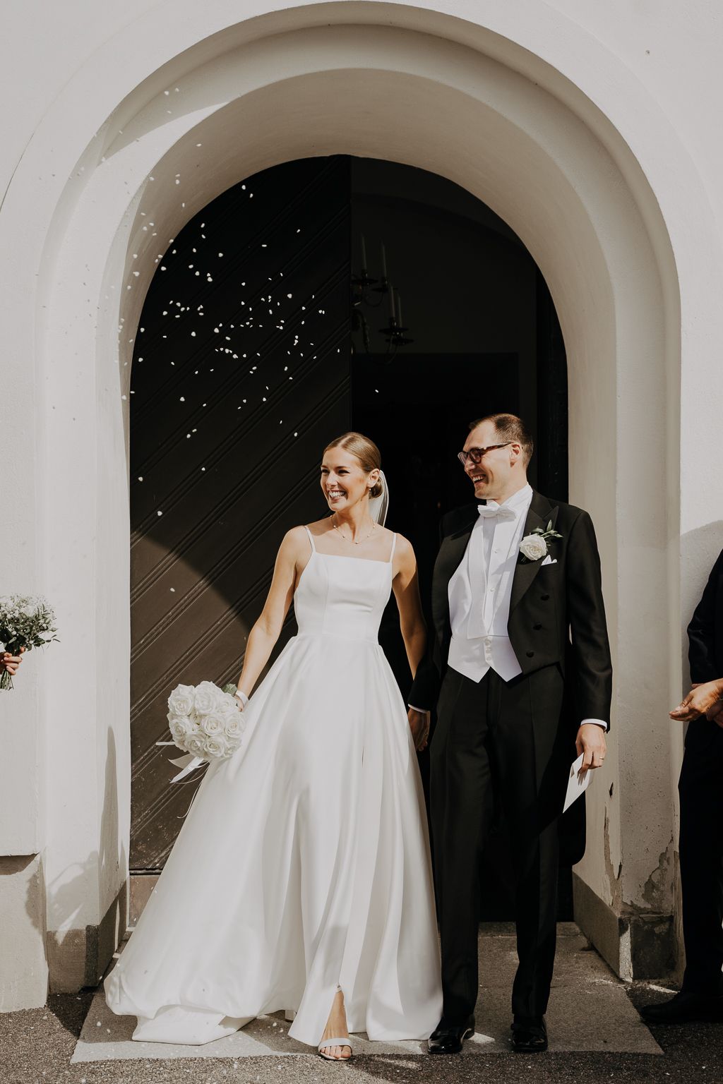 Brudpar utanför kyrka i ett regn av bröllopsris, bröllopsfotografering, Köping utanför Västerås