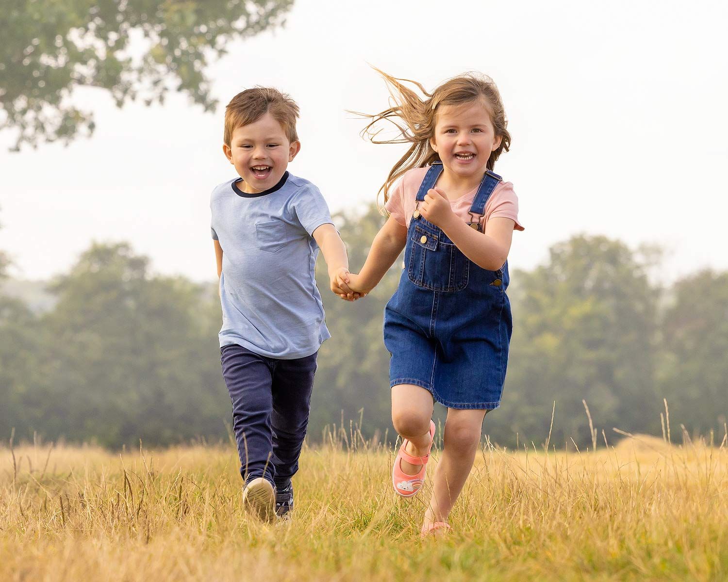 Two happy children running in a field. Suffolk family photographer
