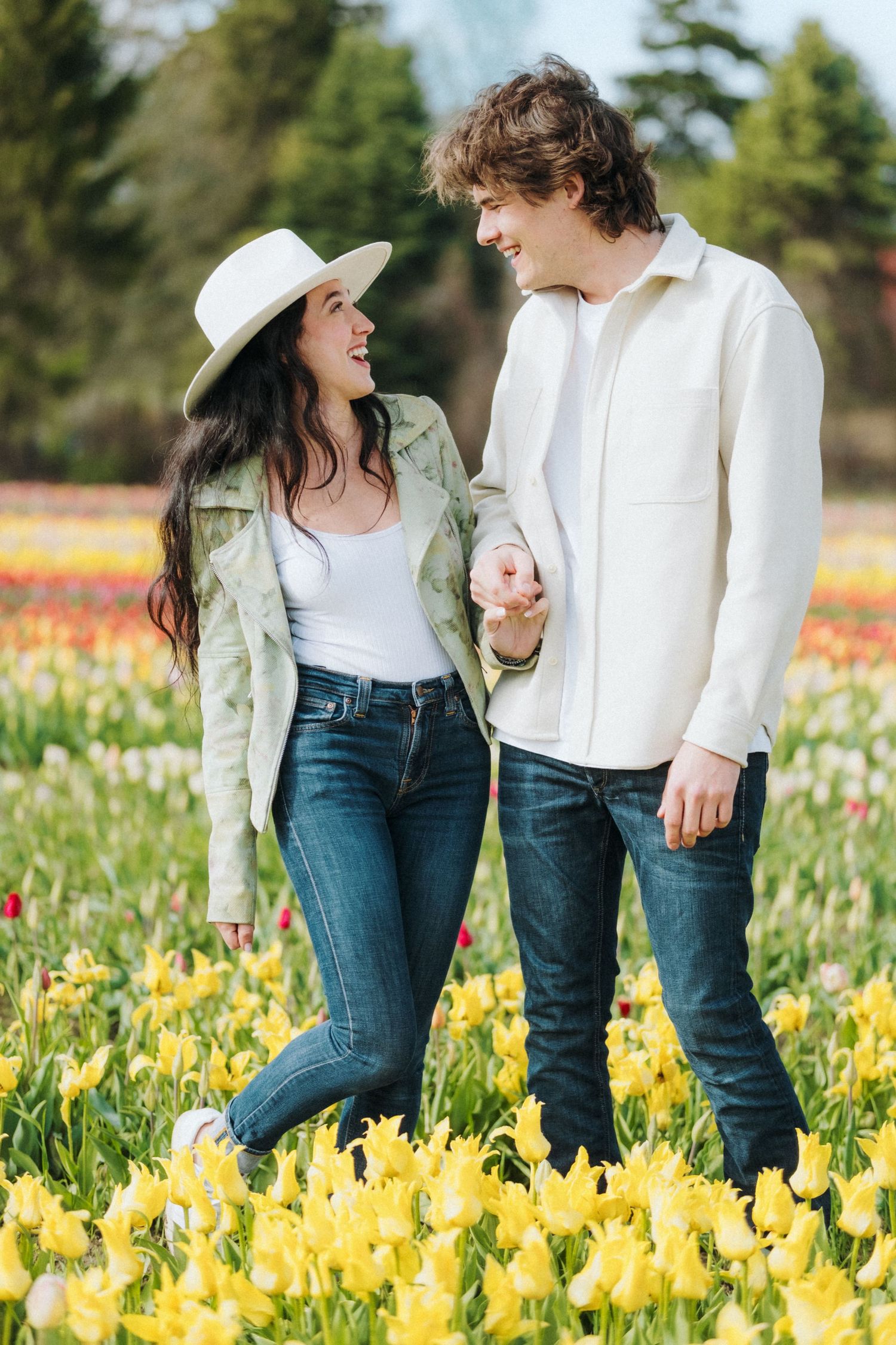 A joyful couple sharing laughter among yellow daffodils in a spring garden.