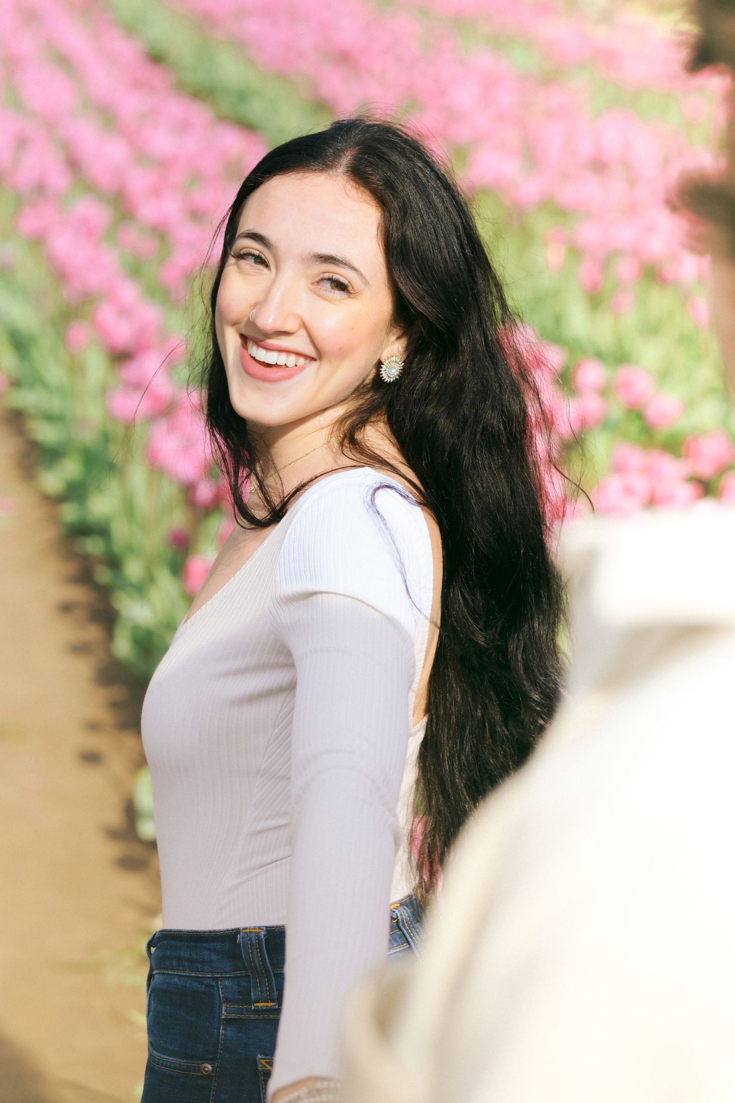 A candid portrait in a pink flower field with a bright natural smile.