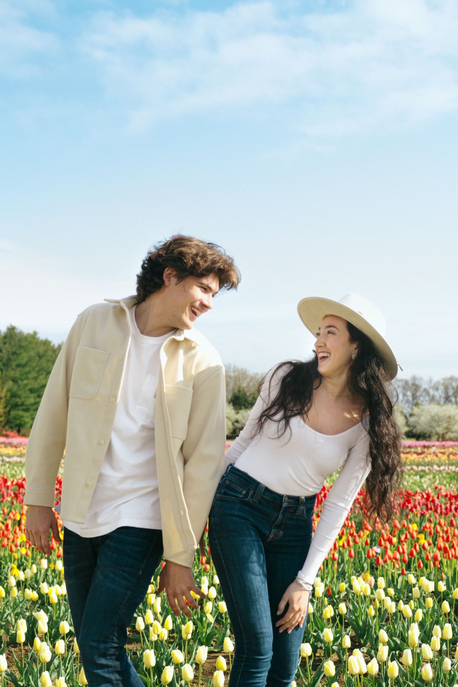 A joyful moment shared between two people in a vibrant tulip field under blue skies.