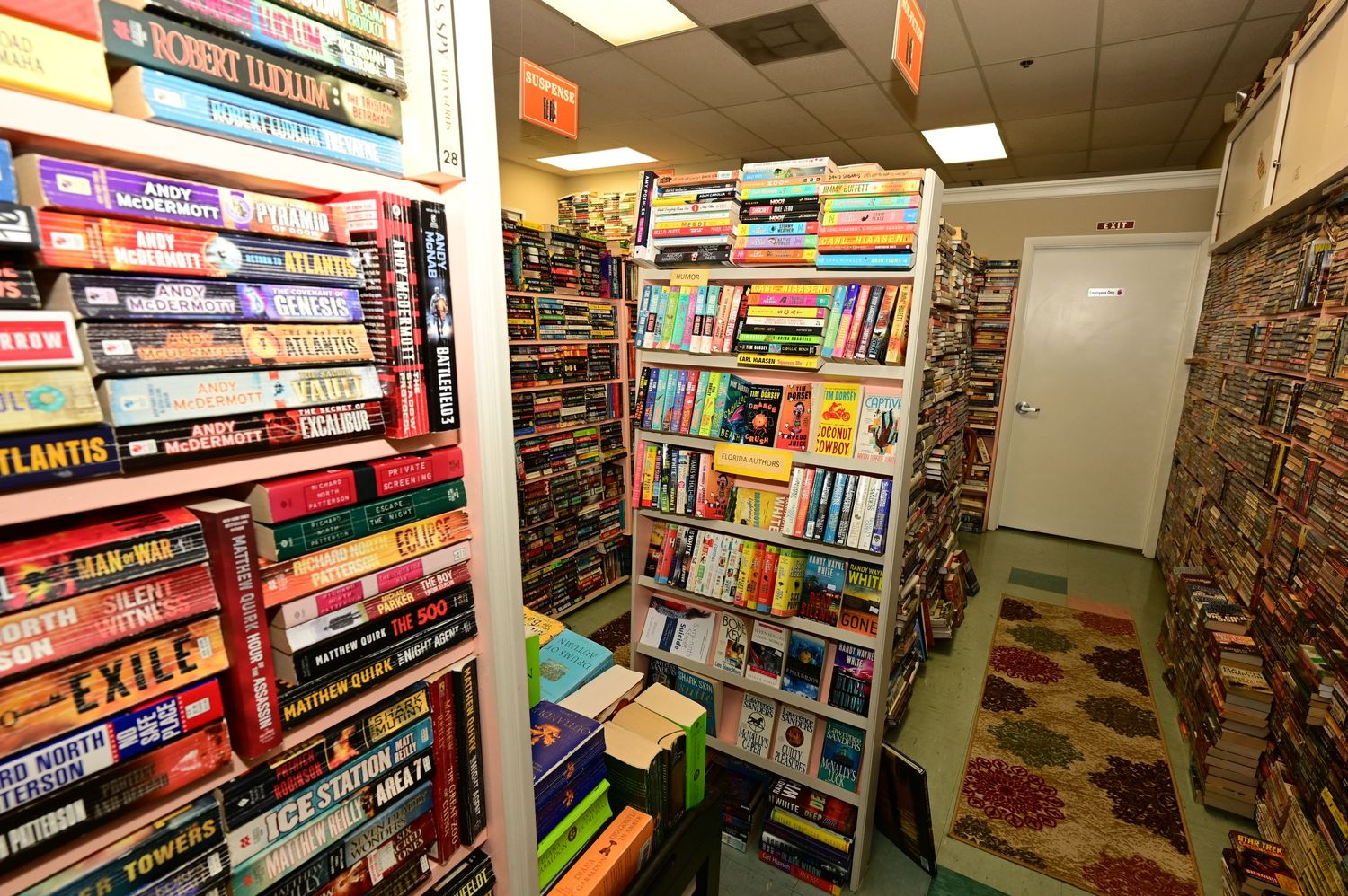 Wide angle shot of a bookstore interior with multiple rows of fully stocked bookshelves.