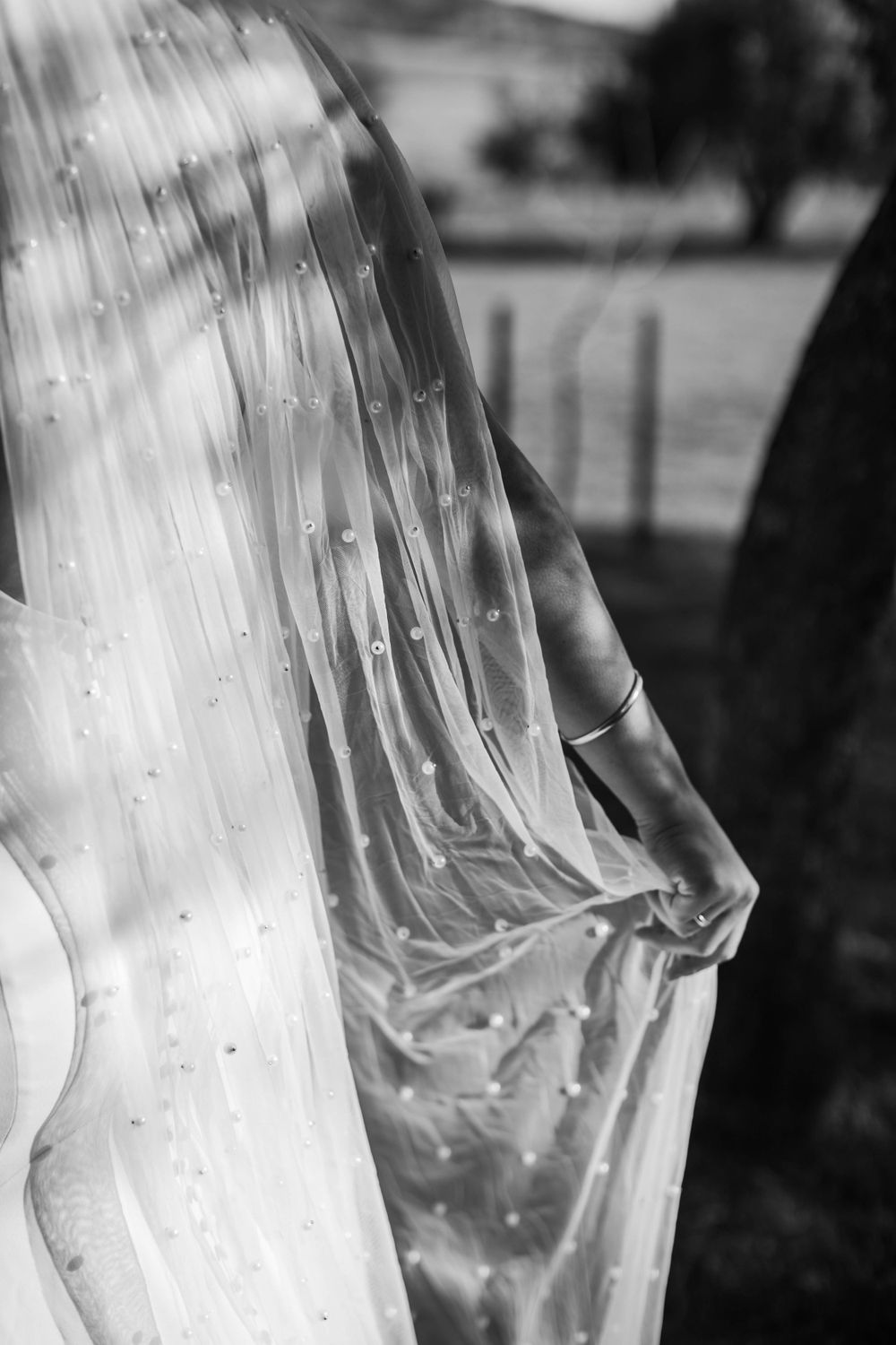 Close-up black and white detail of a bridal veil with scattered pearls or beading.