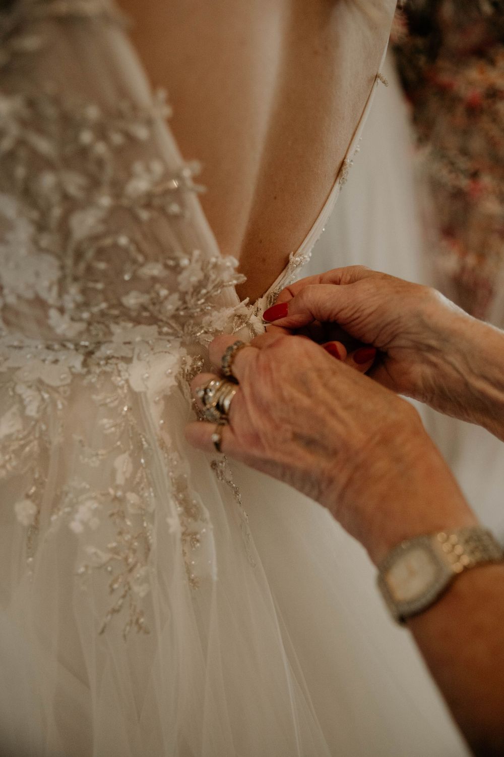 Close-up of hands adjusting delicate lace details on a white wedding dress.