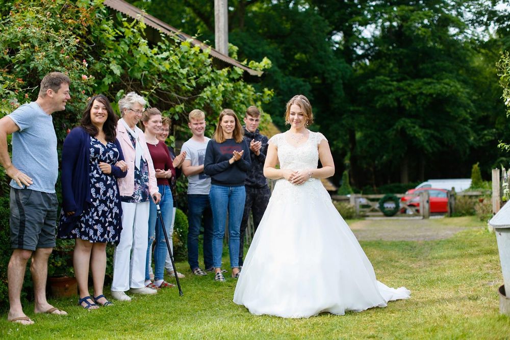 Wedding party guests gather outdoors to celebrate with the bride in her white gown.