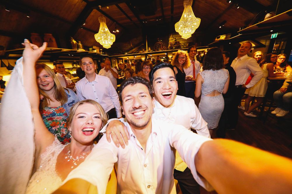 Party guests dance and celebrate under chandeliers at a reception.