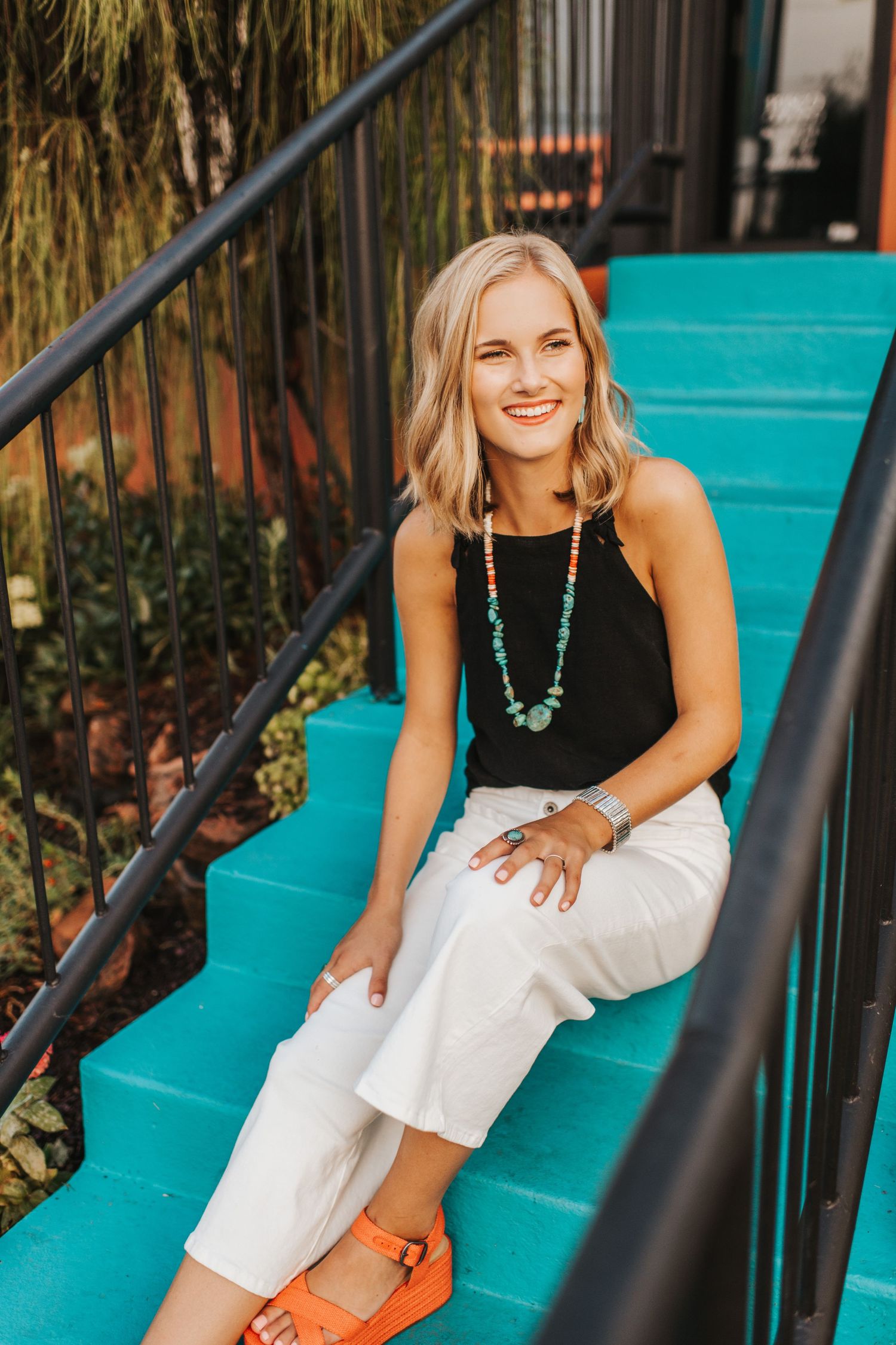 A high school senior posing with confidence on a blue staircase.