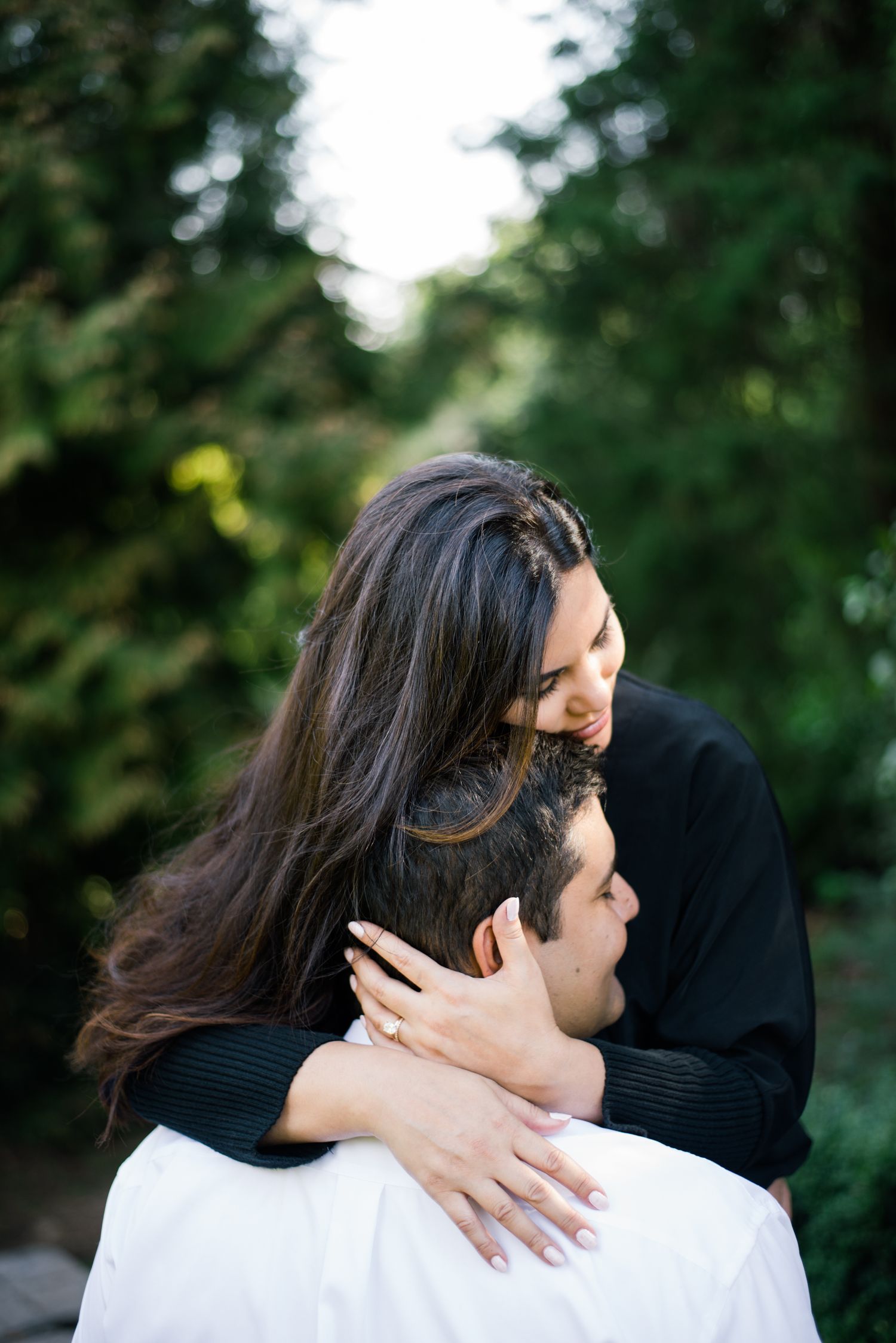 Intimate moment captured between couple embracing outdoors with forest background.