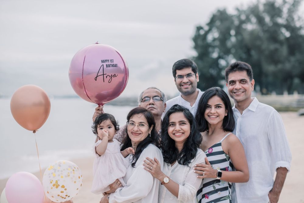 Family gathering on the beach with pink balloons for a birthday celebration.