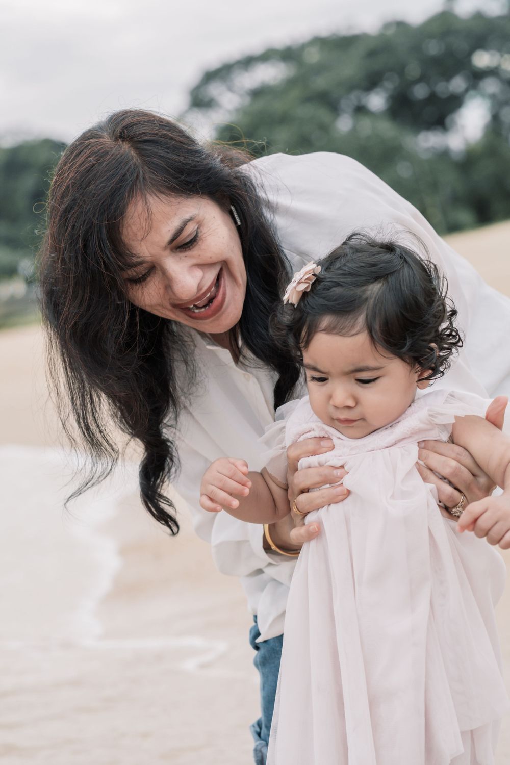 Parent and child share a joyful moment together outdoors in coordinating white outfits.