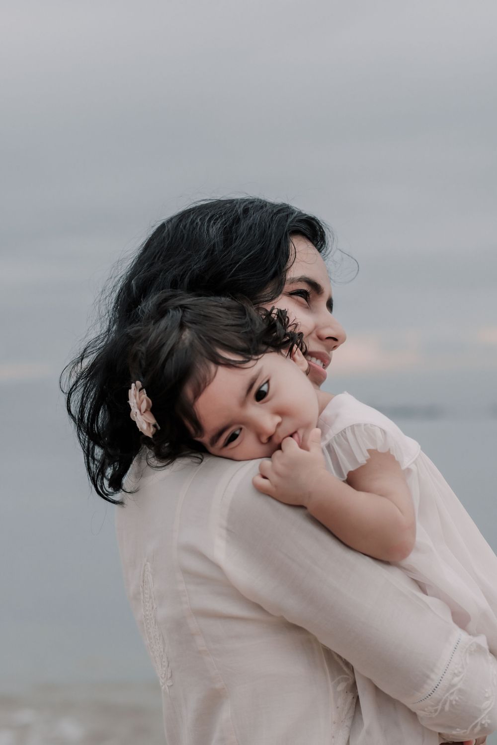Intimate moment between parent and child embracing on a cloudy beach.