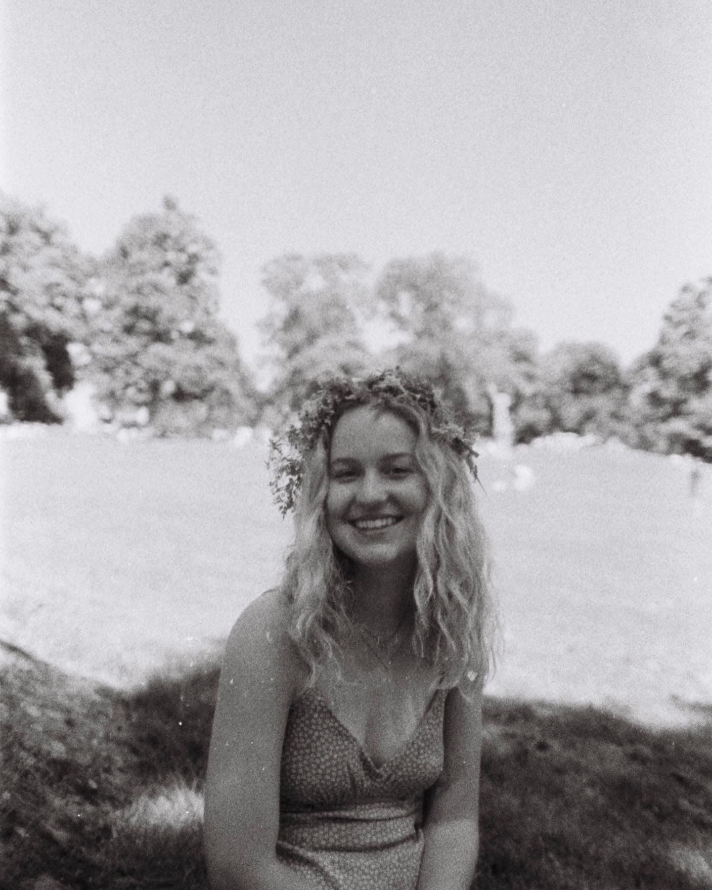 A summer portrait in black and white showing someone wearing a flower crown outdoors.