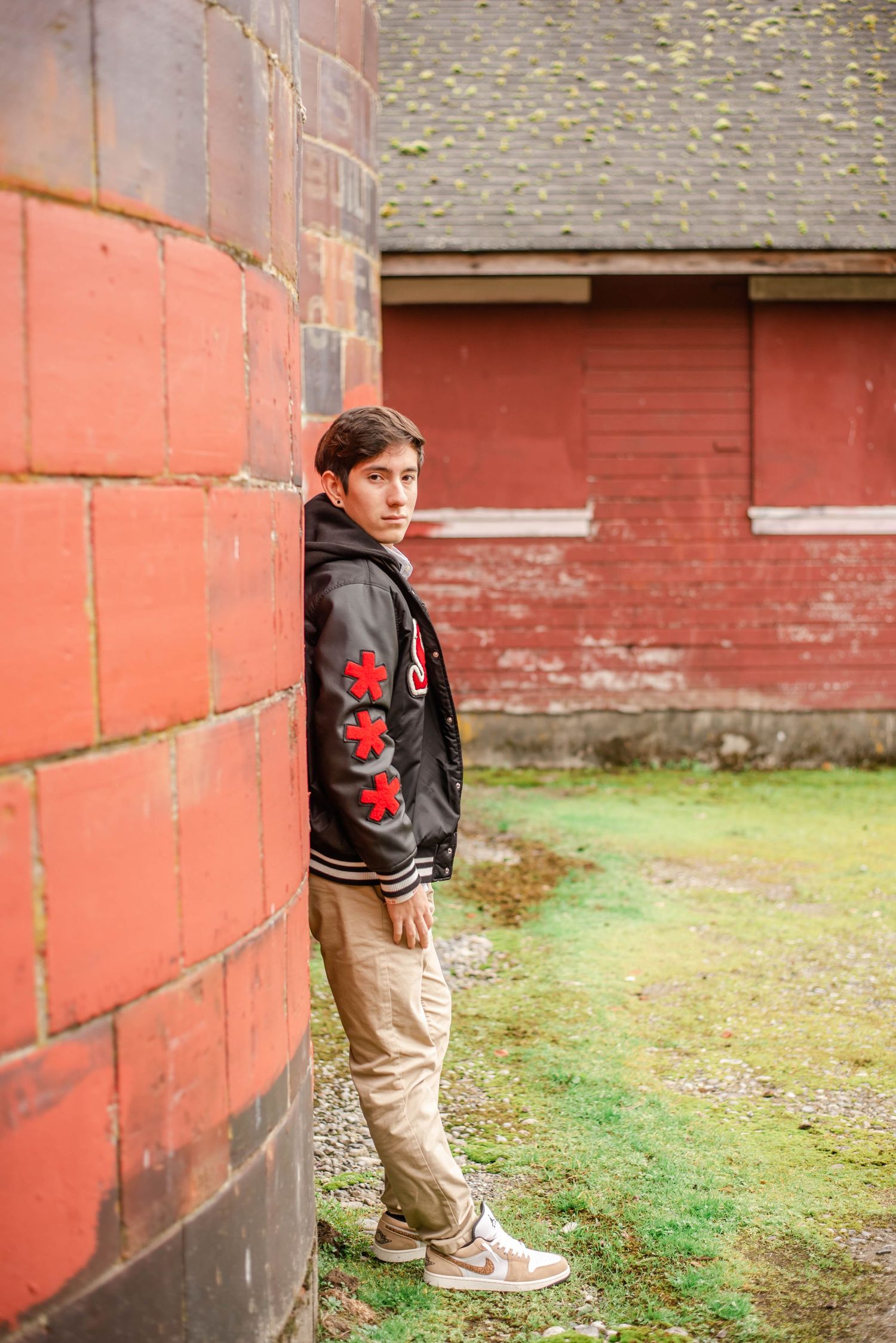 Portrait series against red barn wall wearing casual attire.